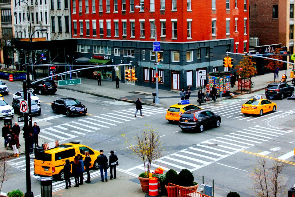 people walking on pedestrian lane near cars and buildings during daytime