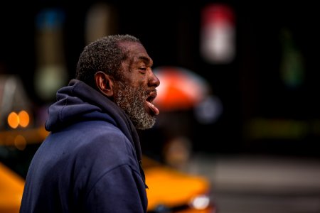man in black hoodie standing on street during daytime photo