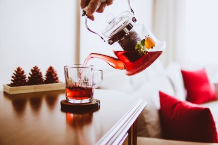 person holding teapot pouring up on glass mug photo