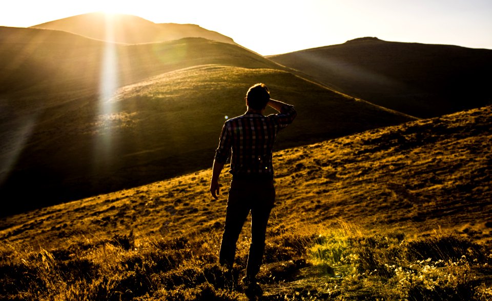 man standing on hill under white sky at daytime