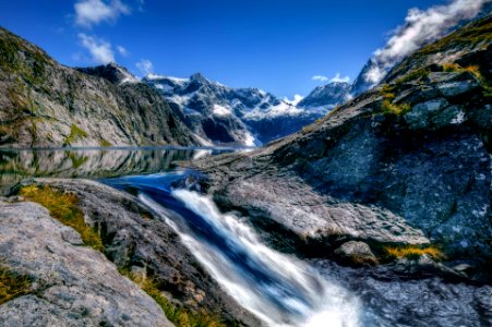 waterfalls surrounded mountain under blue and white skies photo