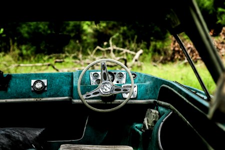 blue and black boat steering wheel interior near green grass field during daytime