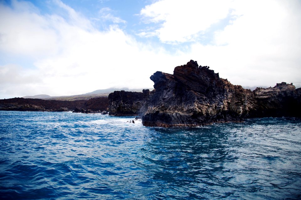 rock in ocean under white sky