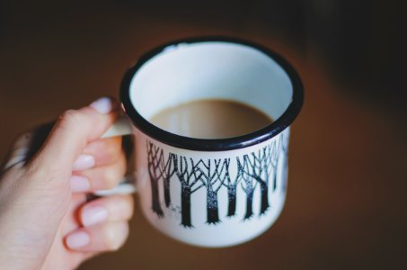 white and black ceramic mug filled with coffee photo
