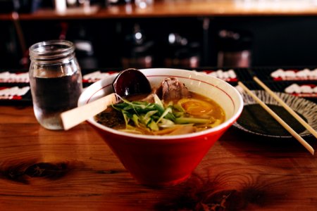 soup with vegetable beside chopsticks and glass of water