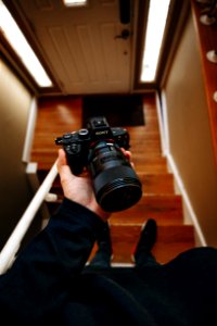 person holding black Sony DSLR camera on stair photo