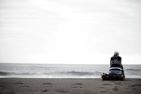 woman sitting near seashore during daytime photo