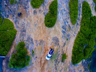 bird's eye view of white car near green hills photo