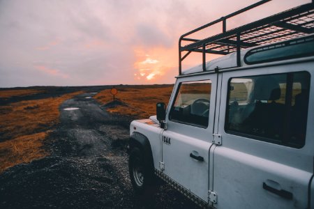 white wrangler with black steel roof rack on gray road