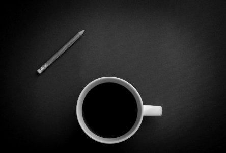 white ceramic teacup near gray pencil on black surface photo