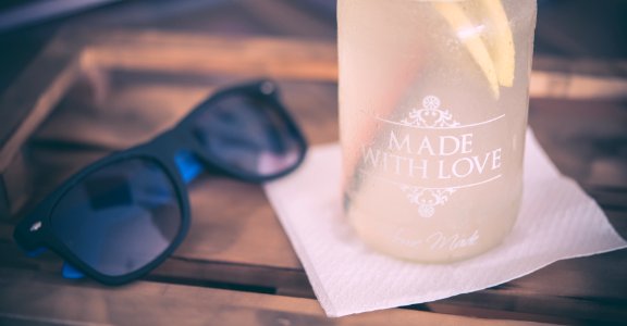 black framed sunglasses beside the glass bottle on table