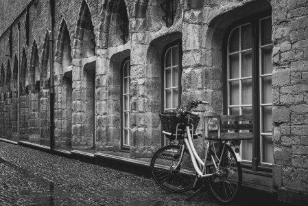 grayscale photo of bike parked beside building photo