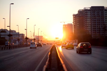 vehicles on highway near buildings during golden hour photo