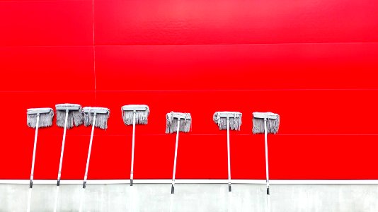 seven white push mops on wall