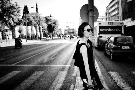 grayscale photo of woman standing beside road signage photo