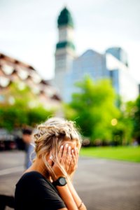 person covering face with hands outdoors photo