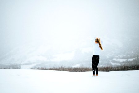 woman standing on open field covered in snow at daytime photo