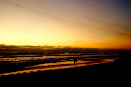person standing on sea shore during golden hour photo