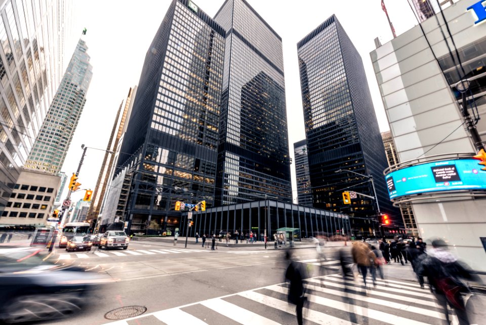 people crossing on pedestrian lane in front high-rise buildings