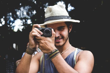 selective focus photo of man holding black compact camera photo