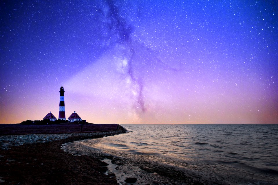 white and red lighthouse near bodies of water at night
