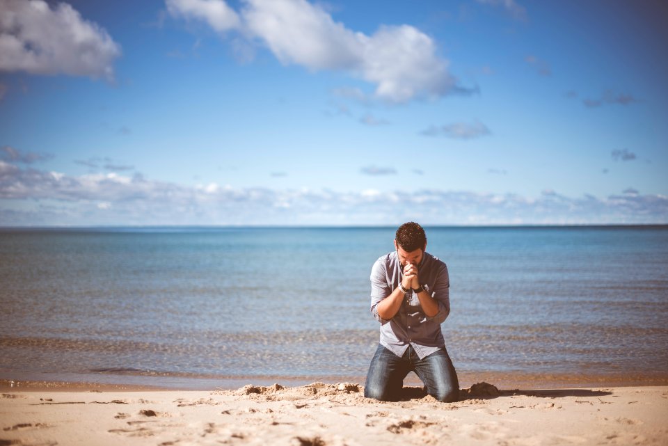 man kneeling down near shore photo