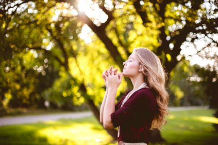 woman praying under tree during daytime photo