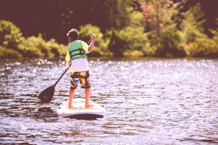 boy riding on surfboard holding black boat oats during daytime photo