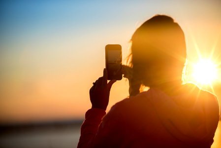 woman taking photo of sunset