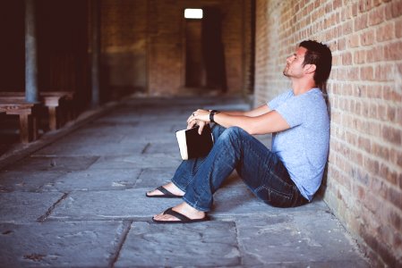 man sitting on pathway holding book at nighttime photo