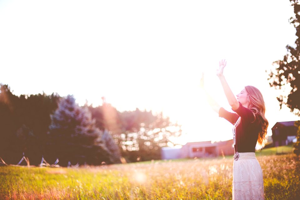 woman hands up in front of green meadows photo