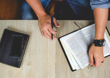 person holding bible with pen photo
