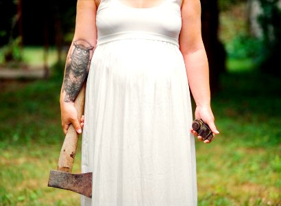 woman in white dress holding axe during daytime photo