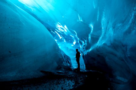 person standing in ice cave at daytime photo