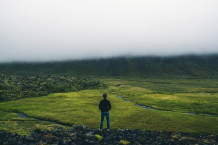 man standing while facing green land photo