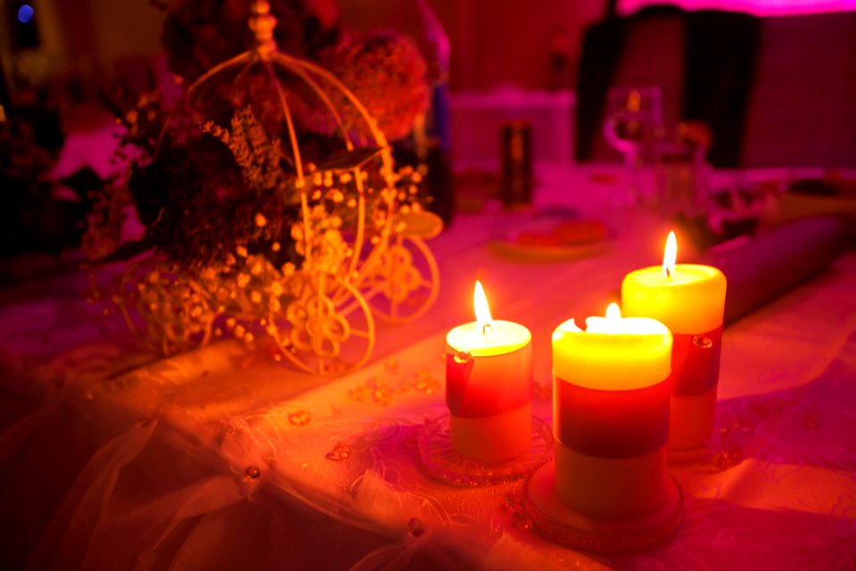 Three lit candles on a table at a princess themed party.