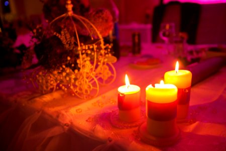 Three lit candles on a table at a princess themed party.