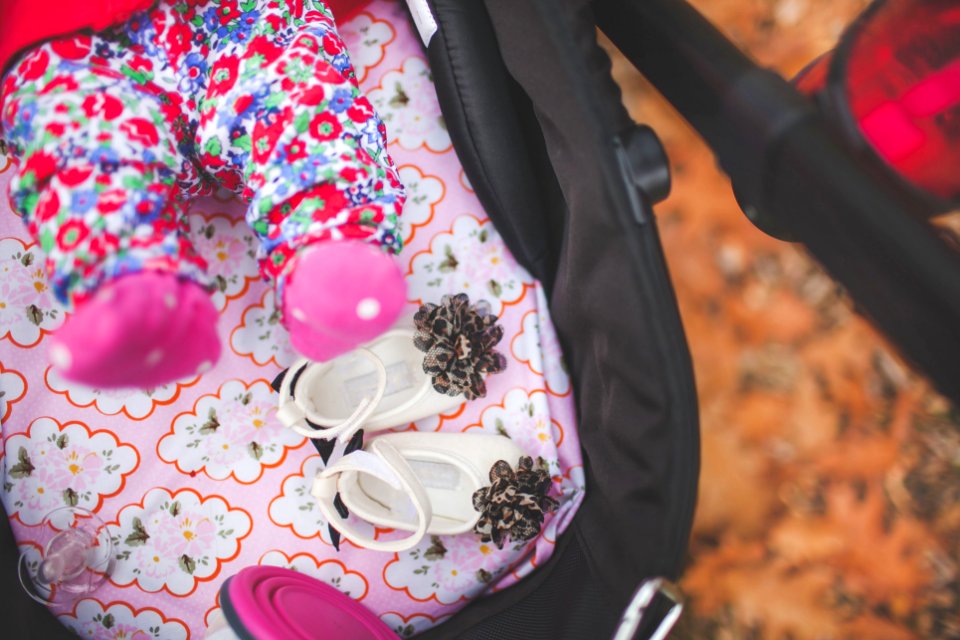 pair of white crib shoes on pink and black stroller