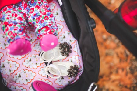 pair of white crib shoes on pink and black stroller photo