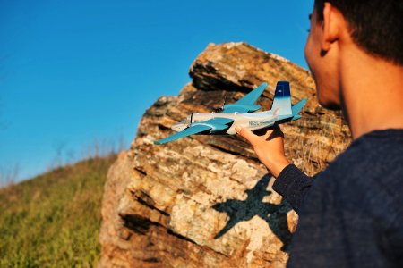 person holding blue airliner beside rock photo