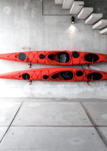 two red kayaks hanging on wall under stairs photo
