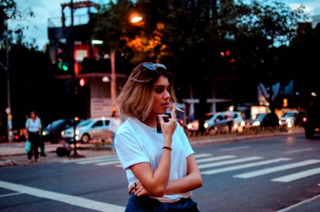woman smoking single cigarette near vehicles and people
