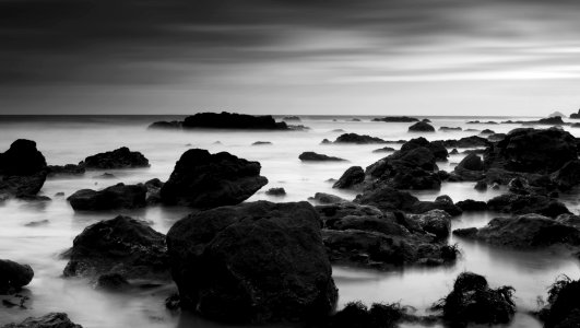 grayscale photography of rocks on body of water