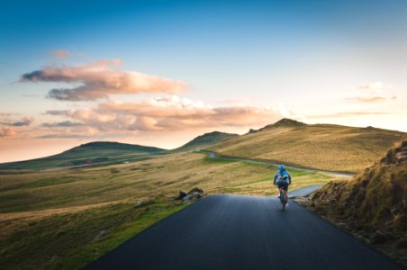 person cycling on road distance with mountain during daytime photo