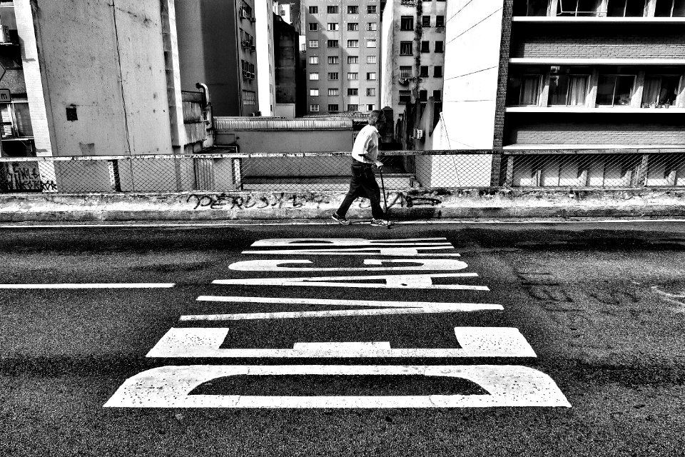 gray scale photography of person walking beside pave road