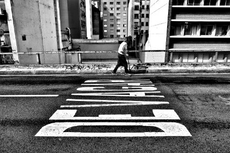 gray scale photography of person walking beside pave road