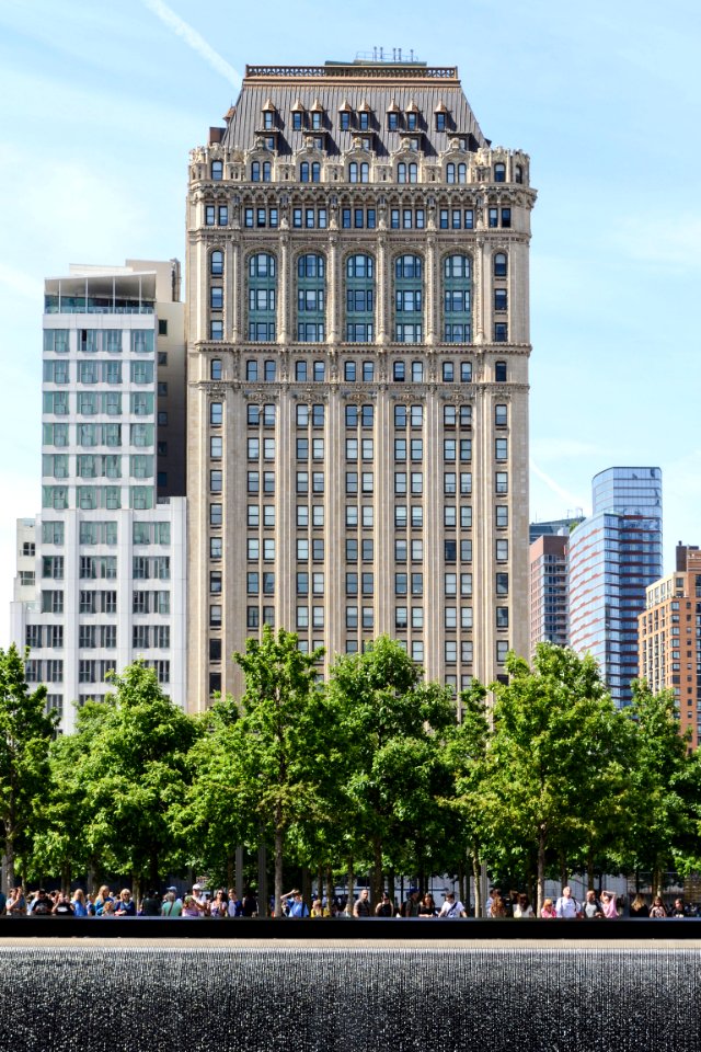 white and gray concrete building with glass windows and green trees on front photo