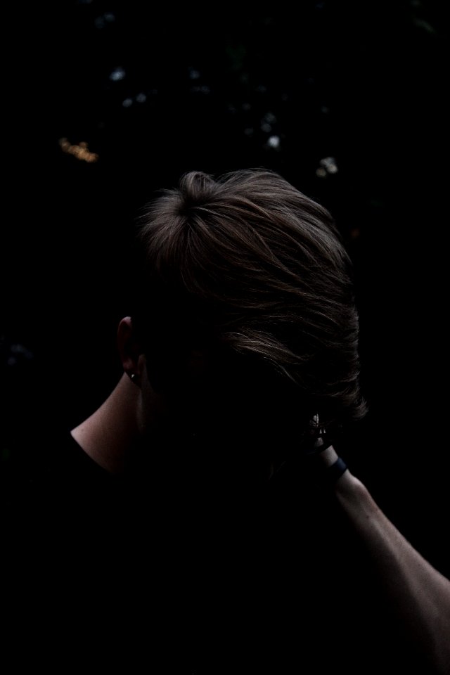 man wearing black shirt and eyeglasses with left hand on neck
