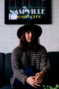 woman sitting on black fabric sofa near Nashville Music City bar mirror photo