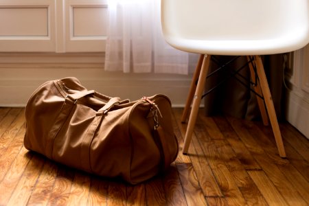 brown duffel bag beside white and brown wooden chair photo